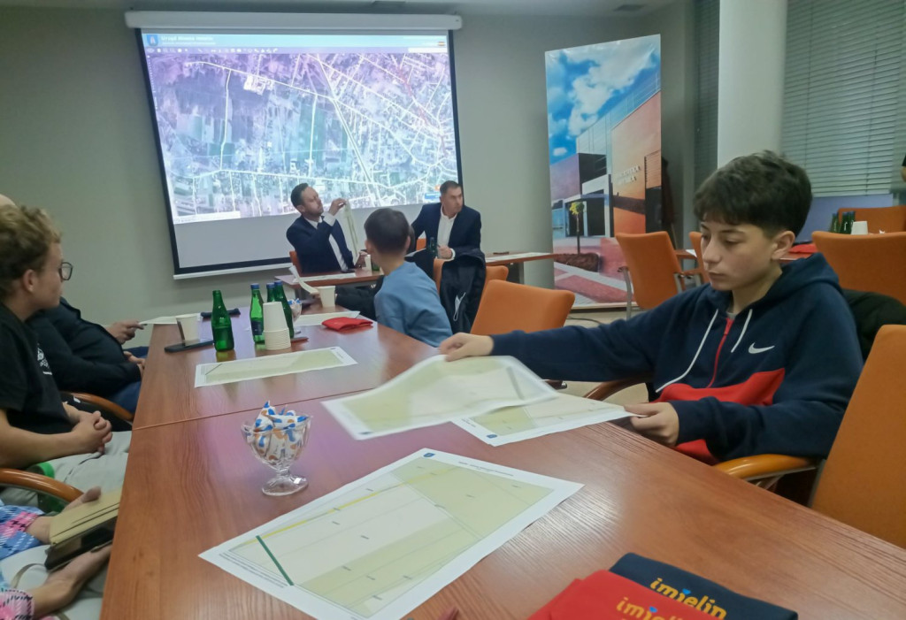 Młody mieszkaniec Imielina analizujący wydrukowane mapy działek przy ul. Spacerowej podczas spotkania